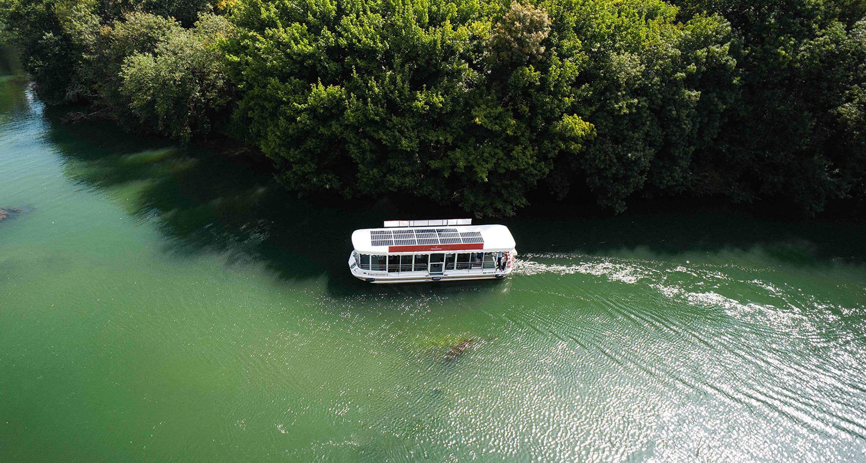 Bateau à énergie solaire Hennessy navigant sur les eaux émeraude de la Charente, à Cognac, en pleine nature