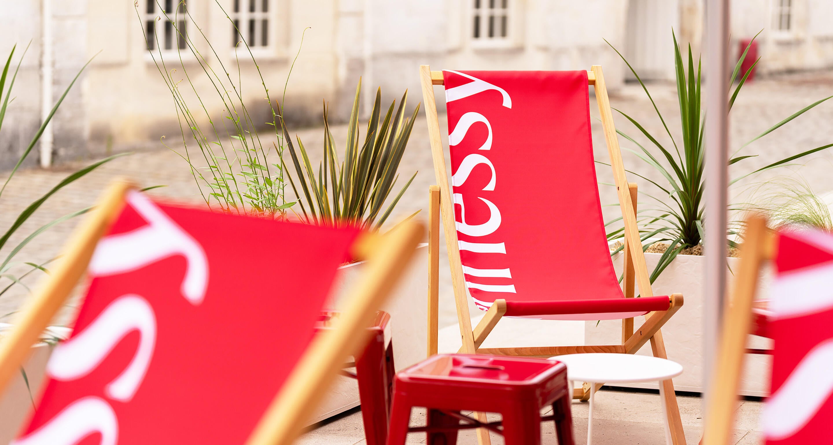 Chaises longues Hennessy en toile rouge et blanche sur la terrasse éphémère estivale de la Boutique Hennessy de Cognac