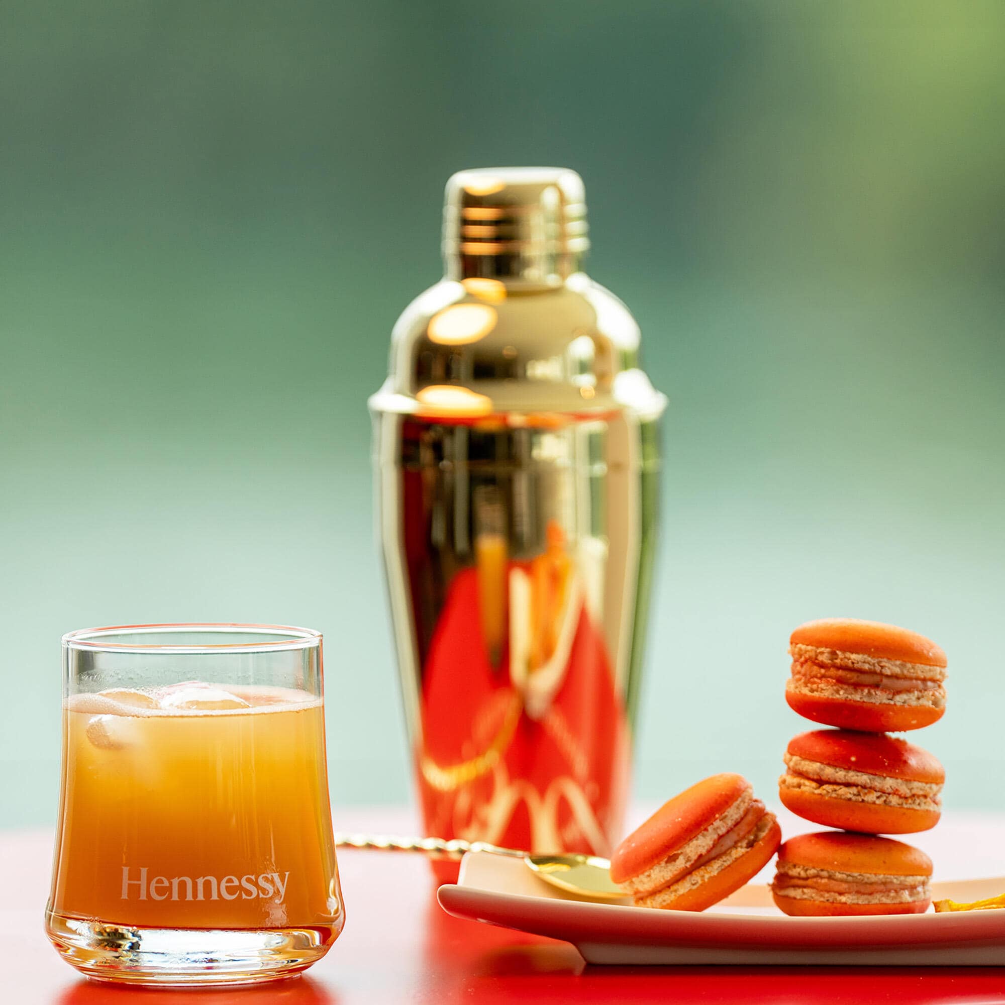 Cocktail Hennessy margarita à côté d'un shaker à cocktail et de macarons Henny-rita créés par le Chef Patissier de la Maison Hennessy, Cyril Baudin