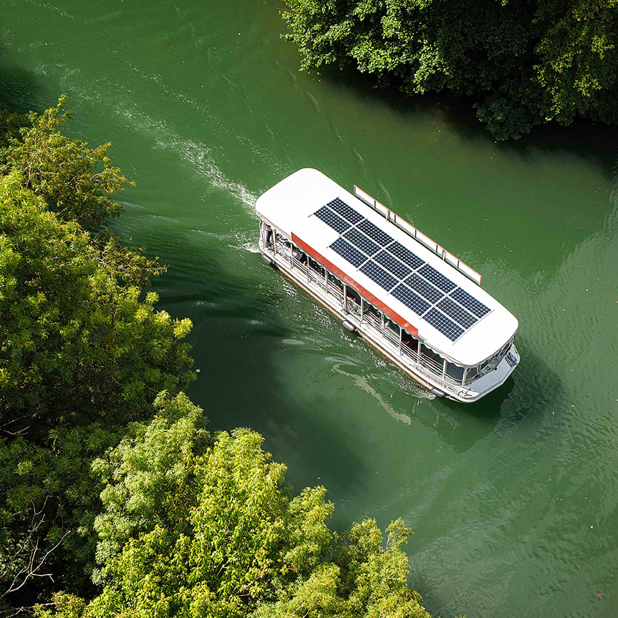 Bateau à énergie solaire Hennessy vu du ciel, navigant sur les eaux émeraude de la Charente, à Cognac, en pleine nature