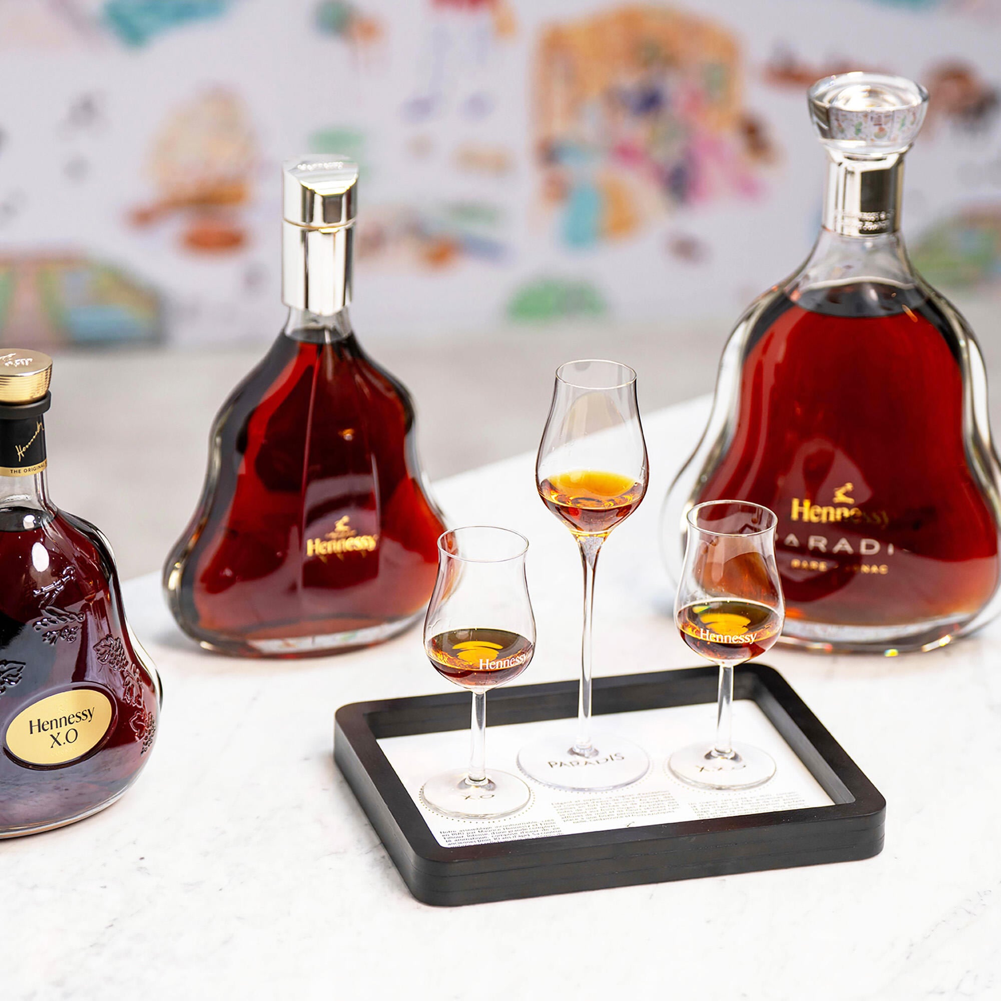Dégustation comparative PRESTIGE : 3 verres de cognac sont posés sur un plateau devant 3 carafes, James Hennessy, Hennessy XO et Hennessy XXO, dans le Bar de la Boutique Hennessy de Cognac