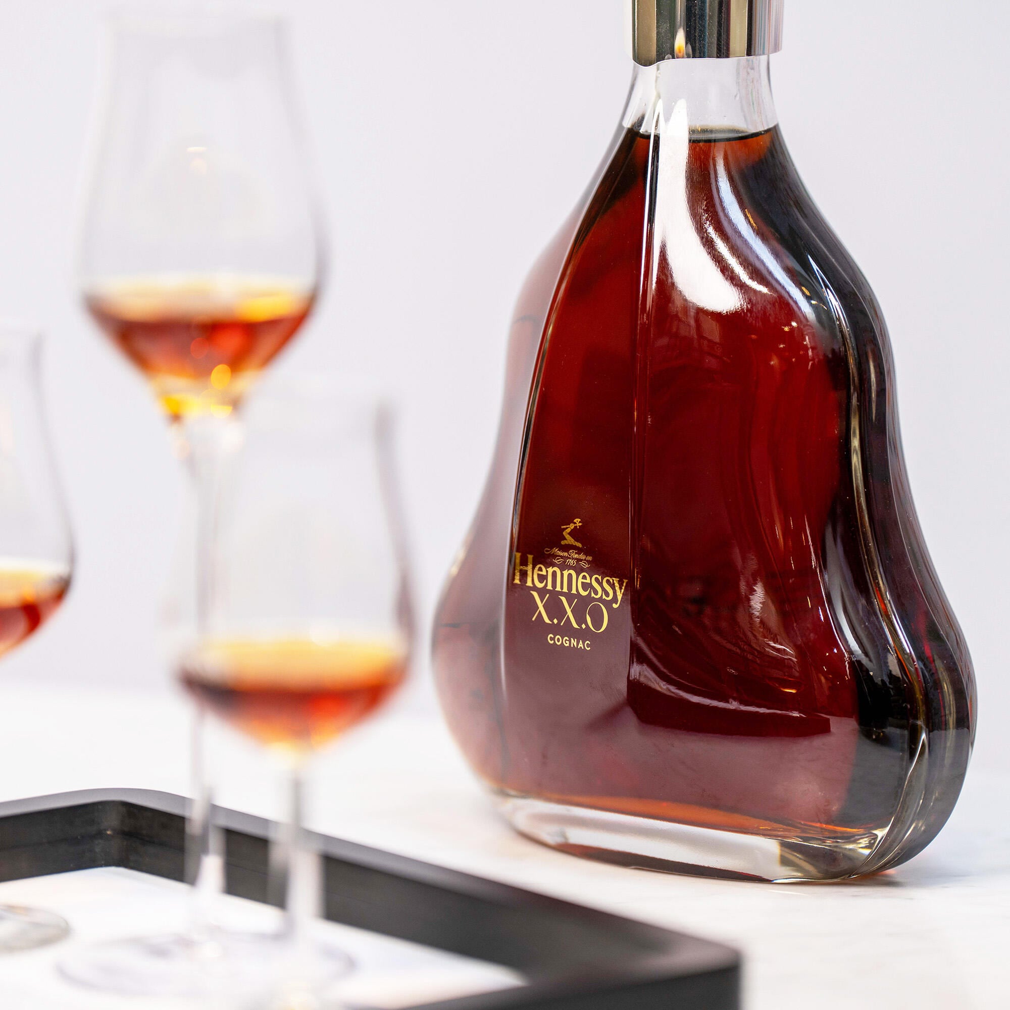 Dégustation comparative ICONIQUE : 3 verres de cognac sont posés sur un plateau devant une carafe de James Hennessy, dans le Bar de la Boutique Hennessy de Cognac