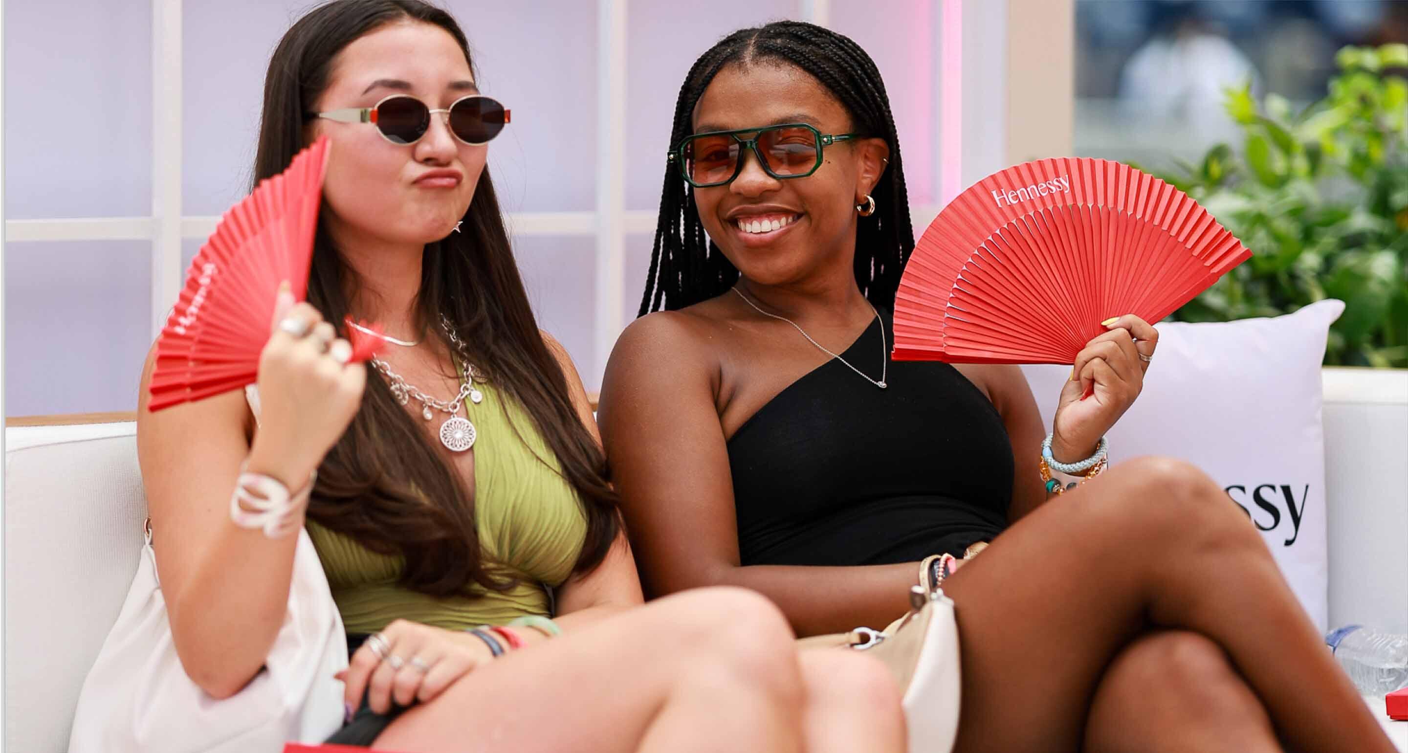 Two customers laughing and relaxing in the plush Hennessy lounge during exclusive brand experiences.