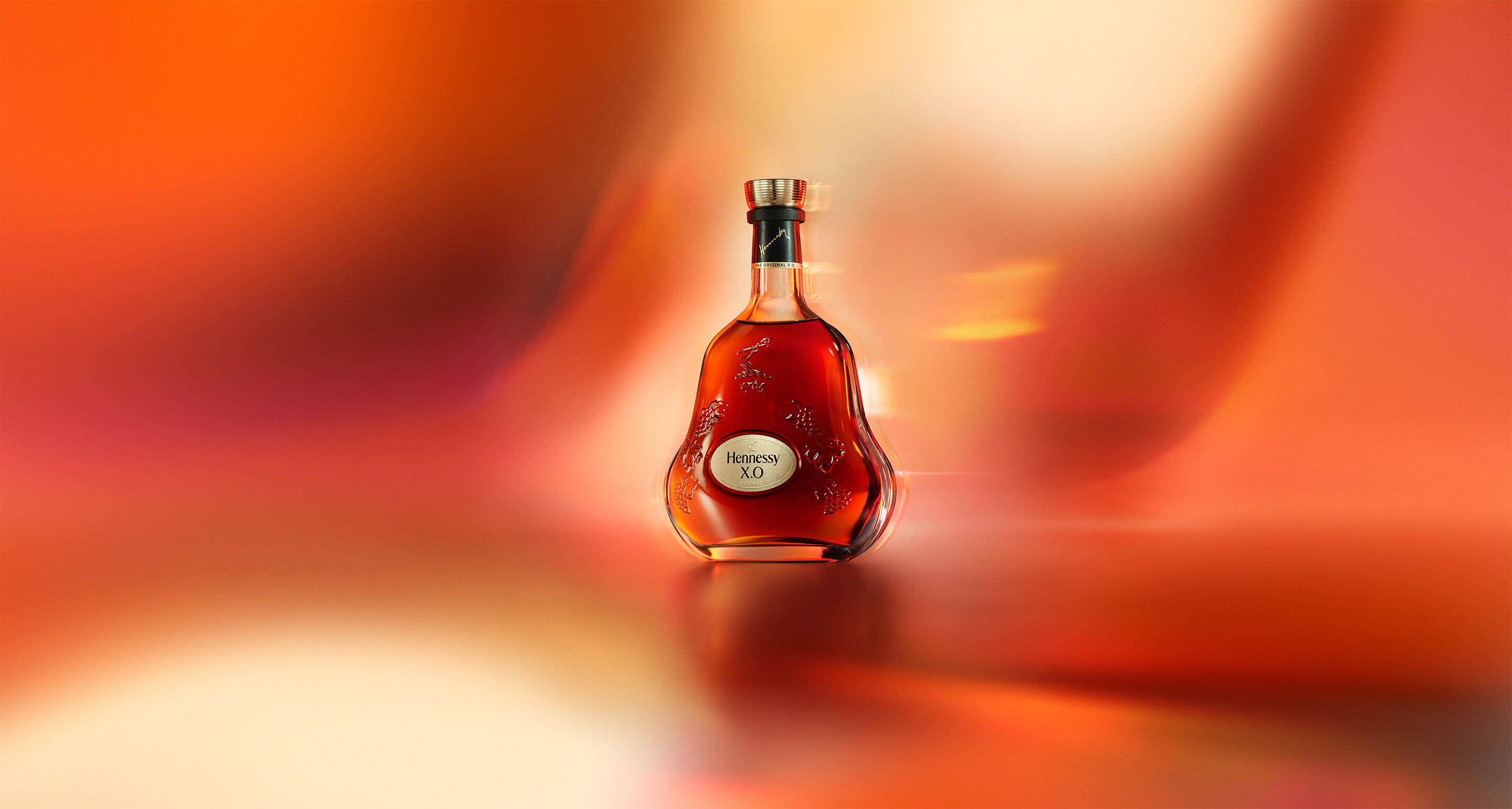 Bottle of Hennessy X.O against a colourful backgroun