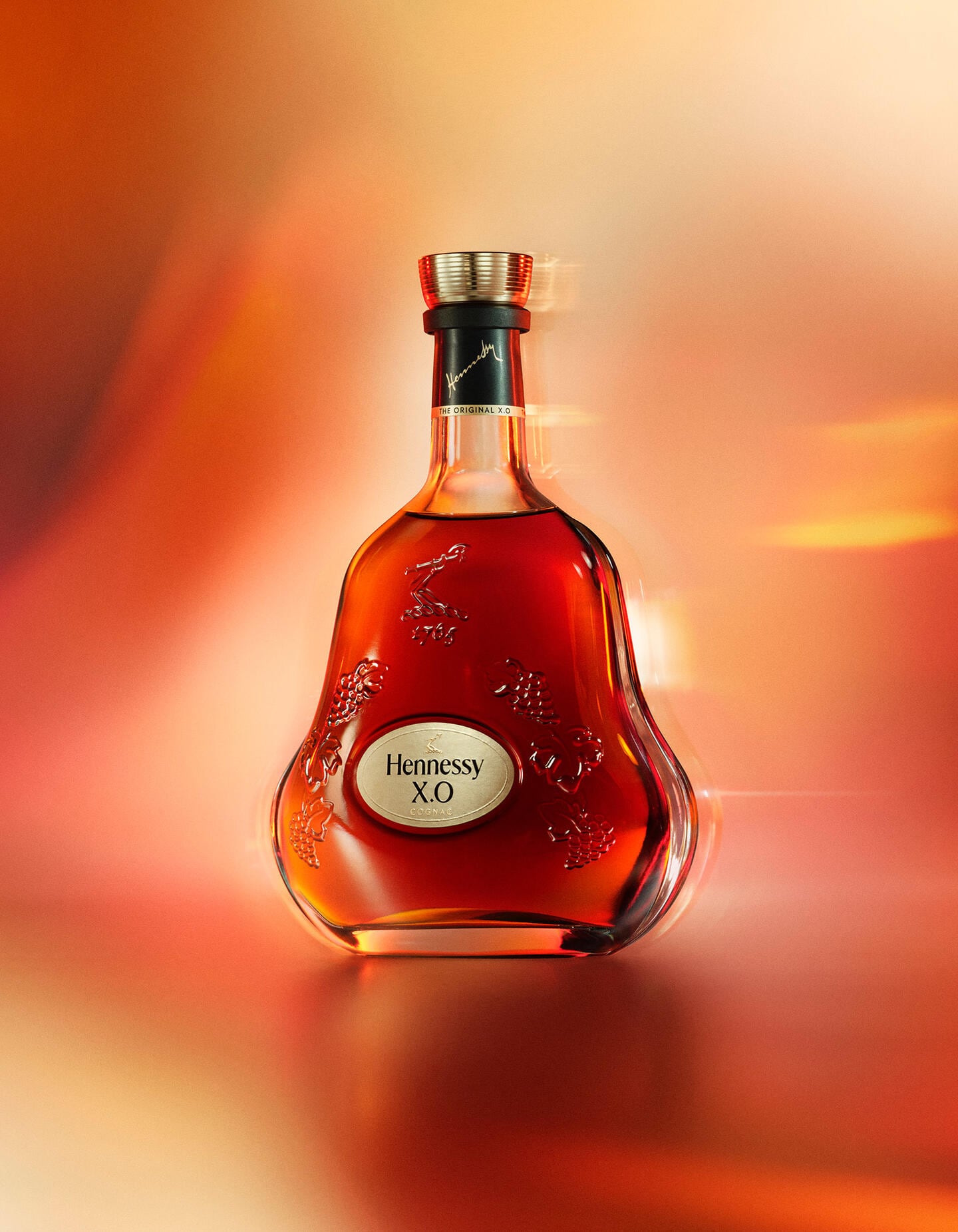 Bottle of Hennessy X.O against a colourful backgroun