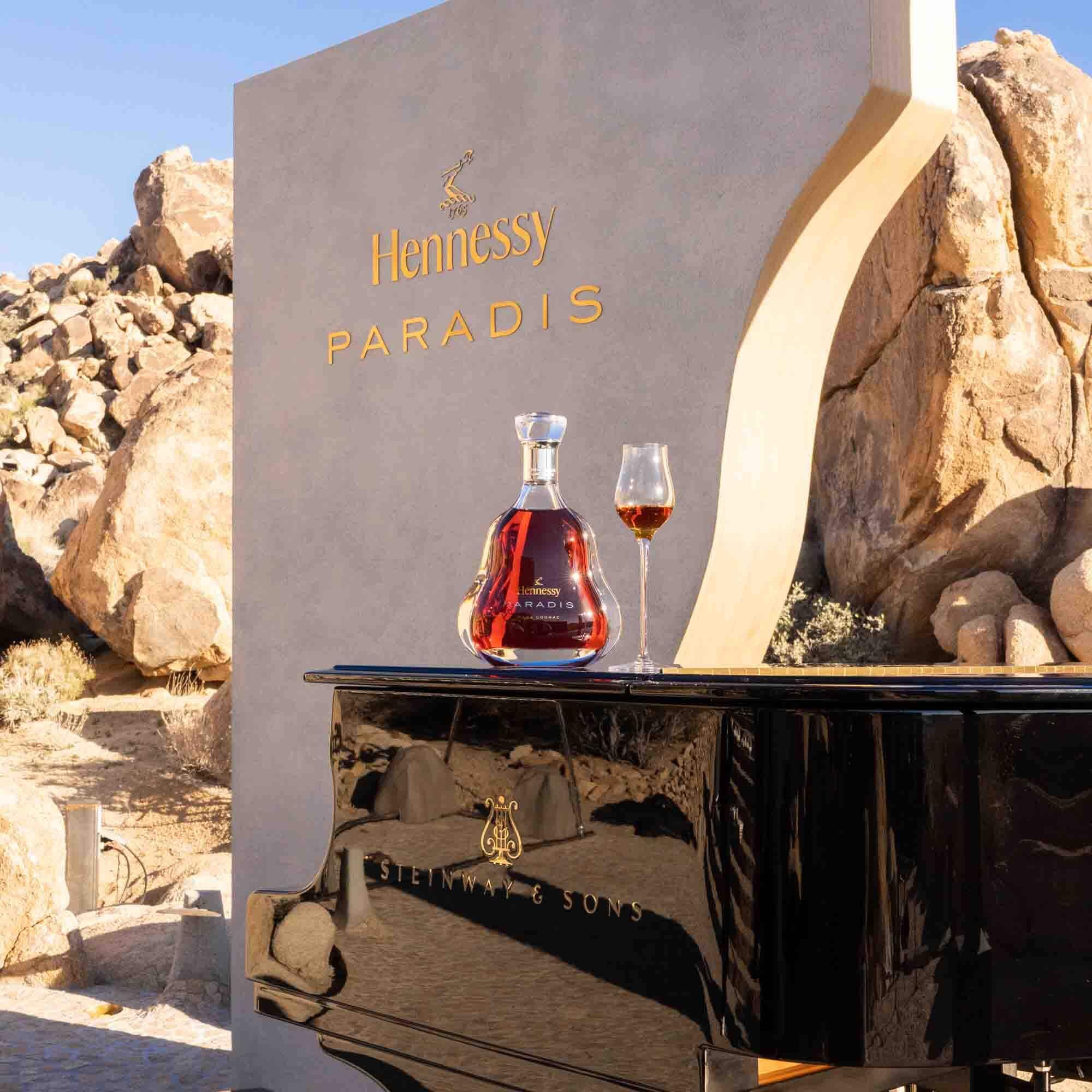 A bottle of Hennessy Paradis and a glass of cognac placed elegantly on a grand piano.