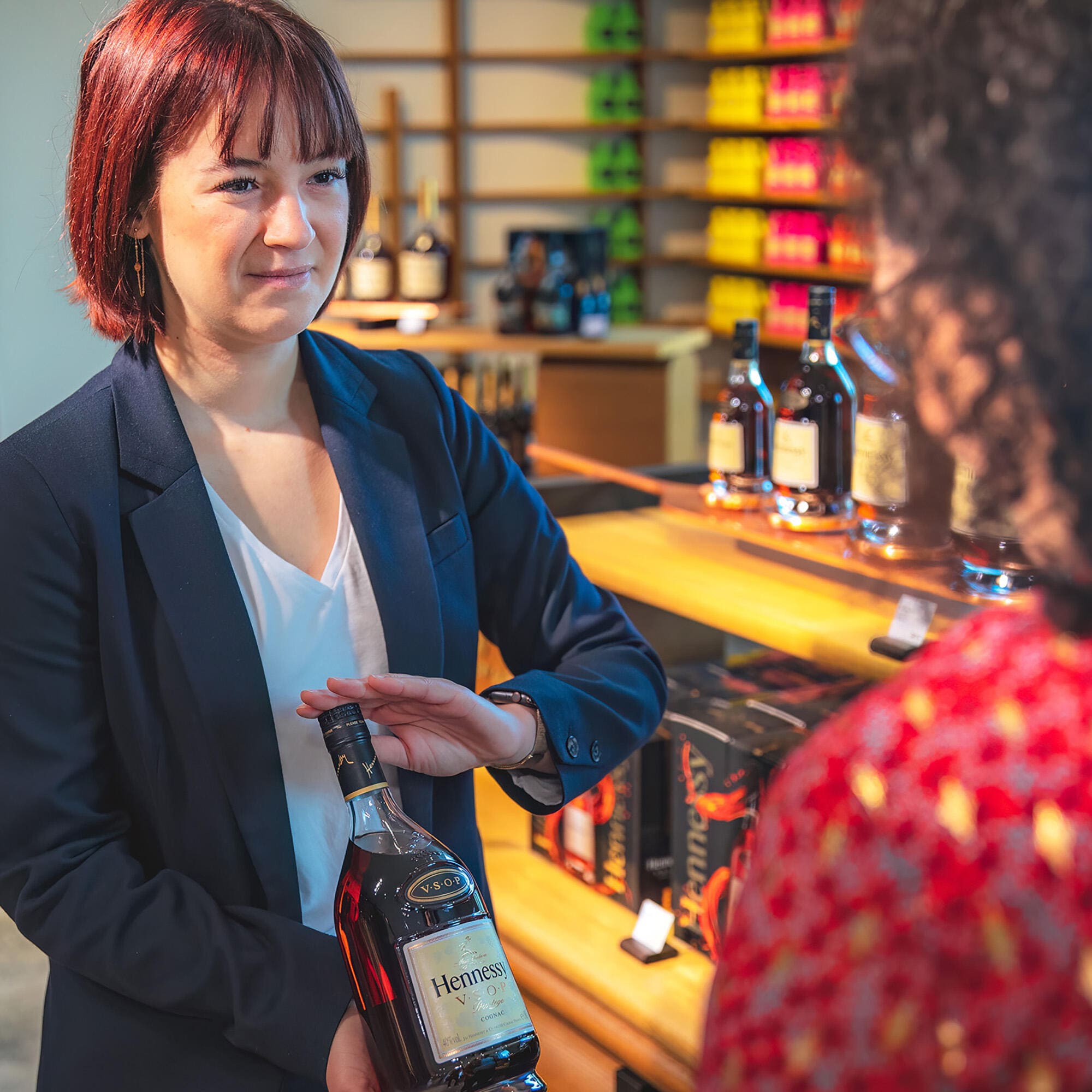 Sales attendant showing a bottle of Hennessy VSOP to a client in the Hennessy flagship store in Cognac